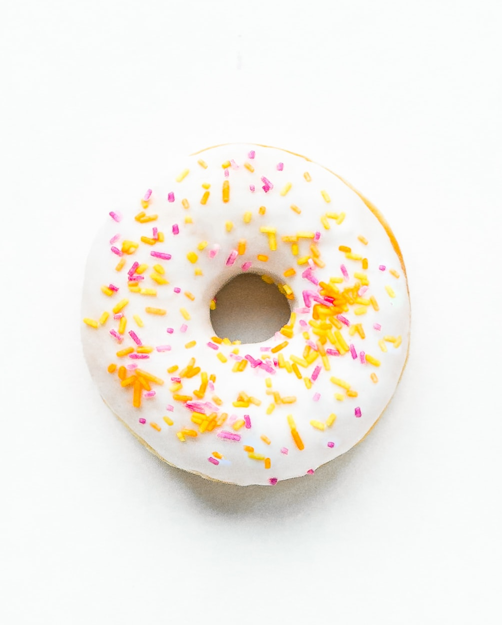 vanilla glaze donut with yellow, orange, and pink sprinkles