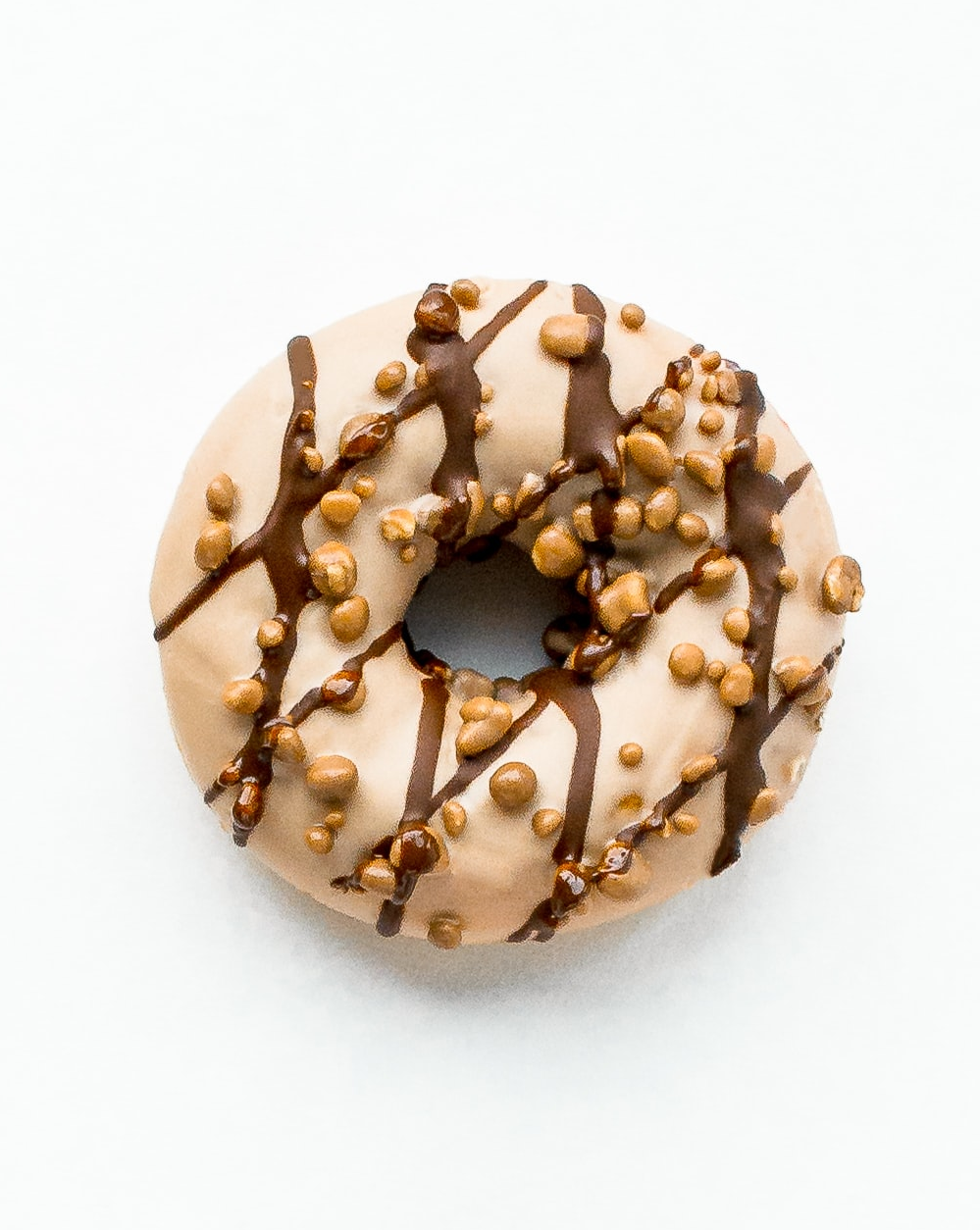 hazelnut glaze donut with chocolate drizzle and nuts